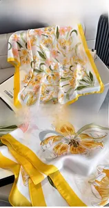 Close-up of vibrant yellow floral print silk scarf featuring premium hemmed edge detail