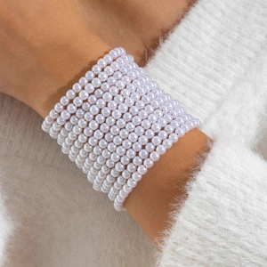 Gros plan d'un élégant bracelet de perles blanches multicouche porté sur un pull