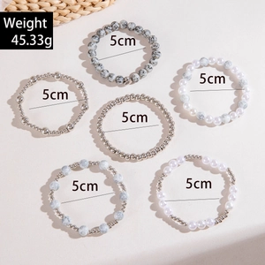 Détail du lot de six bracelets en perles blanches et argentées de 5 cm de diamètre