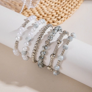 Détail de l'ensemble de cinq bracelets de perles et breloque cœur sur support blanc