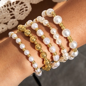 Gros plan d'un ensemble de cinq bracelets en perles multicouches avec perles dorées et baroques