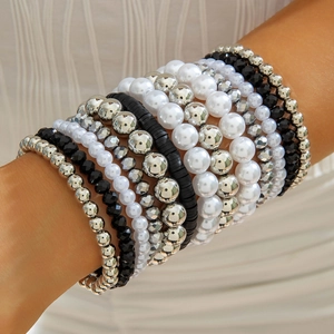 Détail de bracelets perlés multicouches avec perles argentées au poignet d'un mannequin