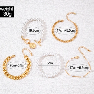 Vue détaillée d'un ensemble de 5 bracelets chaîne dorée et perles avec charms cœur