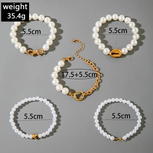 Vue détaillée d'un ensemble de 5 bracelets en perles blanches et breloques dorées avec poids