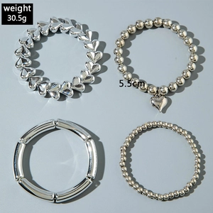 Gros plan sur un ensemble de bijoux argentés quatre pièces avec breloques cœur et perles