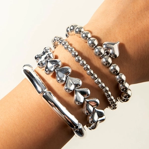 Détail de l'ensemble de bracelets avec breloque cœur argentée et joncs perlés