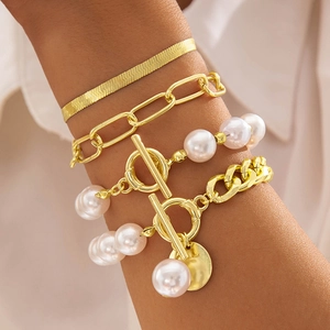 Détail de l'ensemble de quatre bracelets dorés à perles avec fermoir toggle et breloque pièce