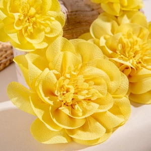 Détail de la fleur en tissu jaune avec pétales superposés et texture réaliste pour boucles