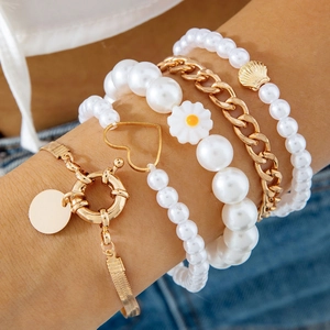 Vue détaillée de bracelets multicouches en chaîne dorée avec perles et breloques cœur