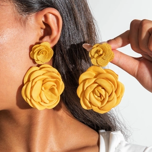 Vue détaillée de boucles d'oreilles roses en tissu jaune double couche sur un modèle