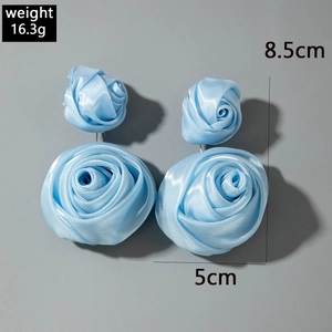Dettaglio orecchini a rosa in tessuto azzurro con dimensioni 8,5 cm e 5 cm su sfondo grigio