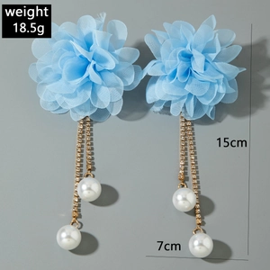 Dettaglio di orecchini a fiore in organza azzurro con nappe dorate e perle bianche