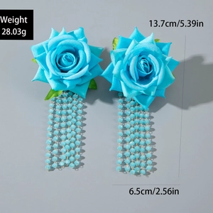 Dettaglio di orecchini a rosa in tessuto blu con nappine di perline e dimensioni esatte