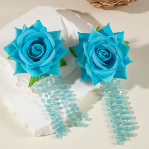 Dettaglio di orecchini rosa in tessuto blu con nappine di perline su pietra