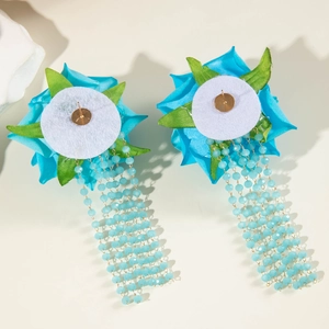 Dettaglio di orecchini floreali con nappe blu e protezione in feltro sul retro