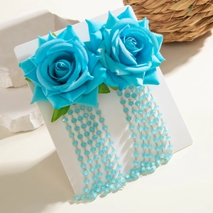 Dettaglio di orecchini a rosa in tessuto blu con nappe di perline su un cartoncino