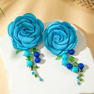 Dettaglio di orecchini a rosa in seta azzurra con nappe pendenti di perline blu e verdi