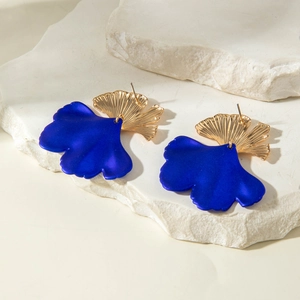 Dettaglio di orecchini a foglia di ginkgo blu con ventaglio dorato su pietre bianche