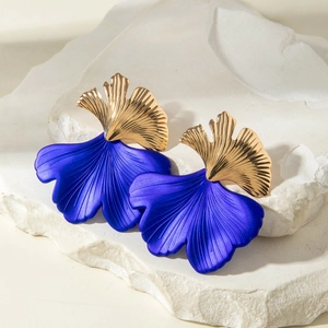 Dettaglio ravvicinato di orecchini a foglia blu e oro con venature e texture realistiche