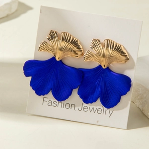 Dettaglio di orecchini a foglia di ginkgo con metallo dorato e petali blu opaco