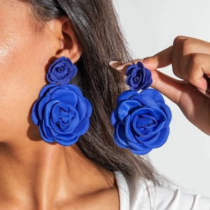 Dettaglio macro di grandi orecchini a rosa 3D blu reale su modella con trama setosa