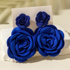 Vista macro degli orecchini a fiore 3D blu reale con petali di rosa in tessuto di seta