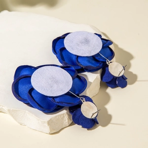 Dettaglio ravvicinato di orecchini a fiore in raso blu su base in pietra naturale