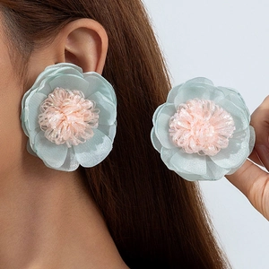 Dettaglio di orecchini floreali in tulle azzurro a strati con stami rosa su modella