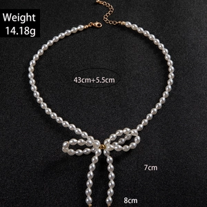 Elegant bow faux pearl necklace with white oval beads and long fringes on black background