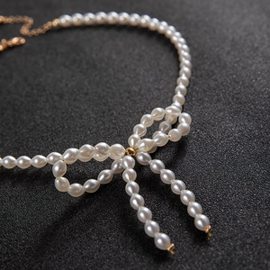 Elegant bow-shaped pearl necklace with high-luster beads and gold adjustable chain