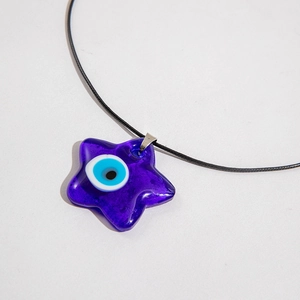 Macro shot of dark purple star-shaped glass pendant with classic evil eye design detail