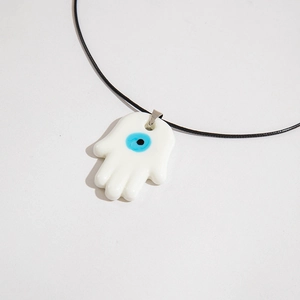 Detailed macro view of the Hamsa Hand pendant with a blue evil eye on a black cord