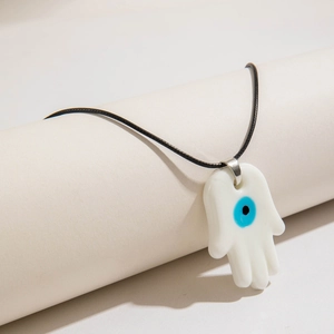 Detail of white Hamsa Hand pendant necklace with blue Evil Eye and black cord
