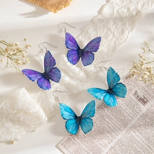 Elegante set di orecchini a farfalla viola e turchese su uno sfondo di pizzo vintage