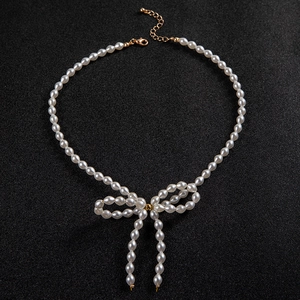 Elegant faux pearl necklace featuring a central pearl bow pendant with drop chains