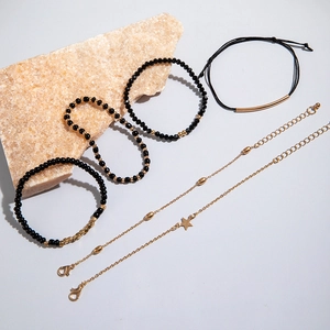 Détail d'un ensemble de 5 bracelets en perles noires avec breloques étoile dorée
