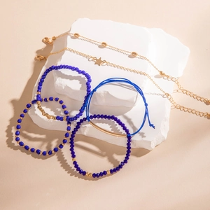 Détail de breloques étoiles dorées et bracelets en perles bleues sur support pierre