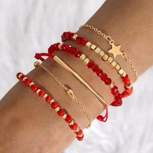 Gros plan de bracelets de perles rouges bohèmes avec étoiles dorées portés au poignet