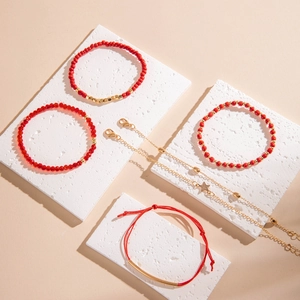 Détail de l'ensemble de bracelets en perles rouges avec pendentif étoile dorée sur pierre
