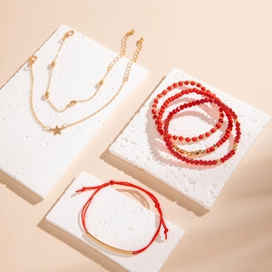 Détail d'un ensemble de bracelets en perles rouges et d'étoiles dorées sur socles en pierre