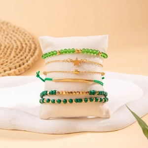 Détail d'un lot de 6 bracelets bohèmes avec étoiles dorées et perles vertes sur un coussinet