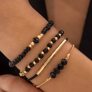 Gros plan d'un ensemble de bracelets en perles noires et tubes dorés au poignet