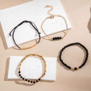 Détail d'un ensemble de quatre bracelets en perles noires et dorées avec accents