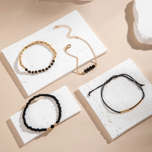 Détail d'un ensemble de quatre bracelets en perles noires avec accents dorés sur pierre