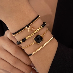Détail d'un ensemble de quatre bracelets en perles noires avec breloques dorées