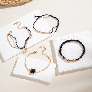 Détail d'un ensemble de bracelets bohèmes en perles noires et dorées sur pierre