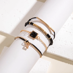 Vue détaillée d'un ensemble de 4 bracelets vintage noirs et dorés avec breloques perles