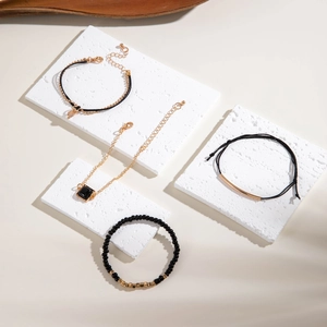 Vue détaillée de 4 bracelets vintage en perles noires et dorées sur pierre blanche