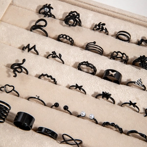 Gothic black ring set with snake spider and butterfly motifs on beige velvet display
