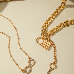 Macro detail of gold layered necklaces with infinity symbol and heart key padlock pendant